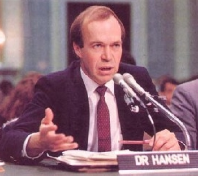 James Hansen, a white man in a suit and tie, speaking in to a set of microphones.