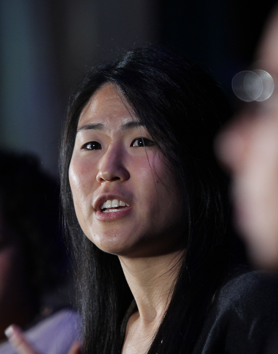 Close up picture of a person speaking seriously on a stage between fellow panelists