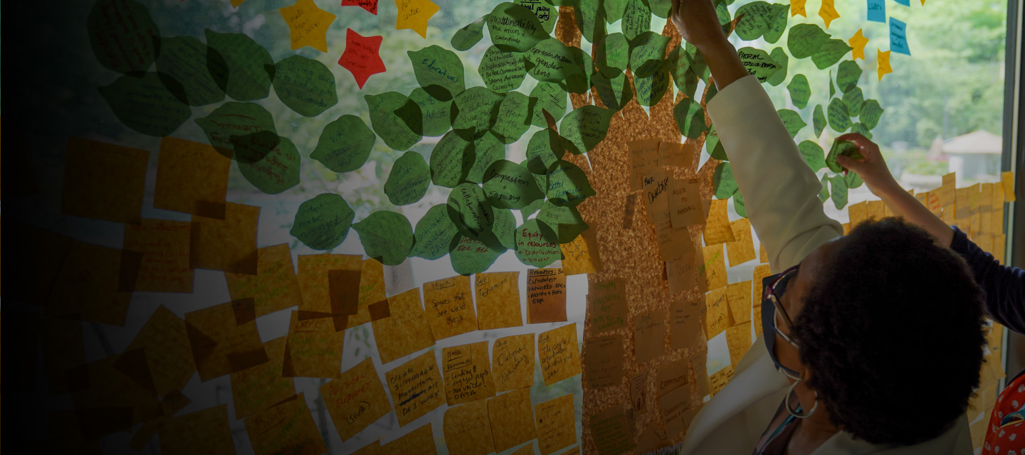 Person putting a note among other notes making up a field with a tree.