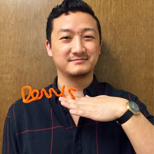 Dennis Chin holding an orange pipe cleaner spelling out his name.