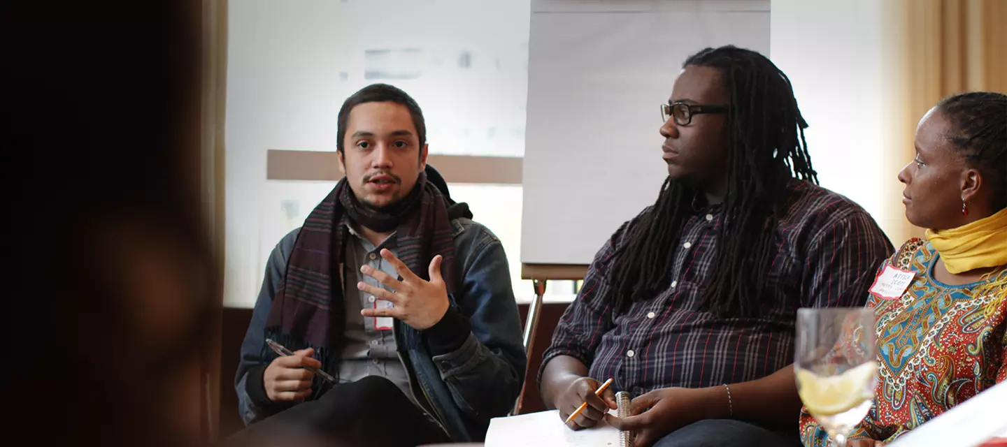 Three seated panelists speaking and listening in the middle of a training