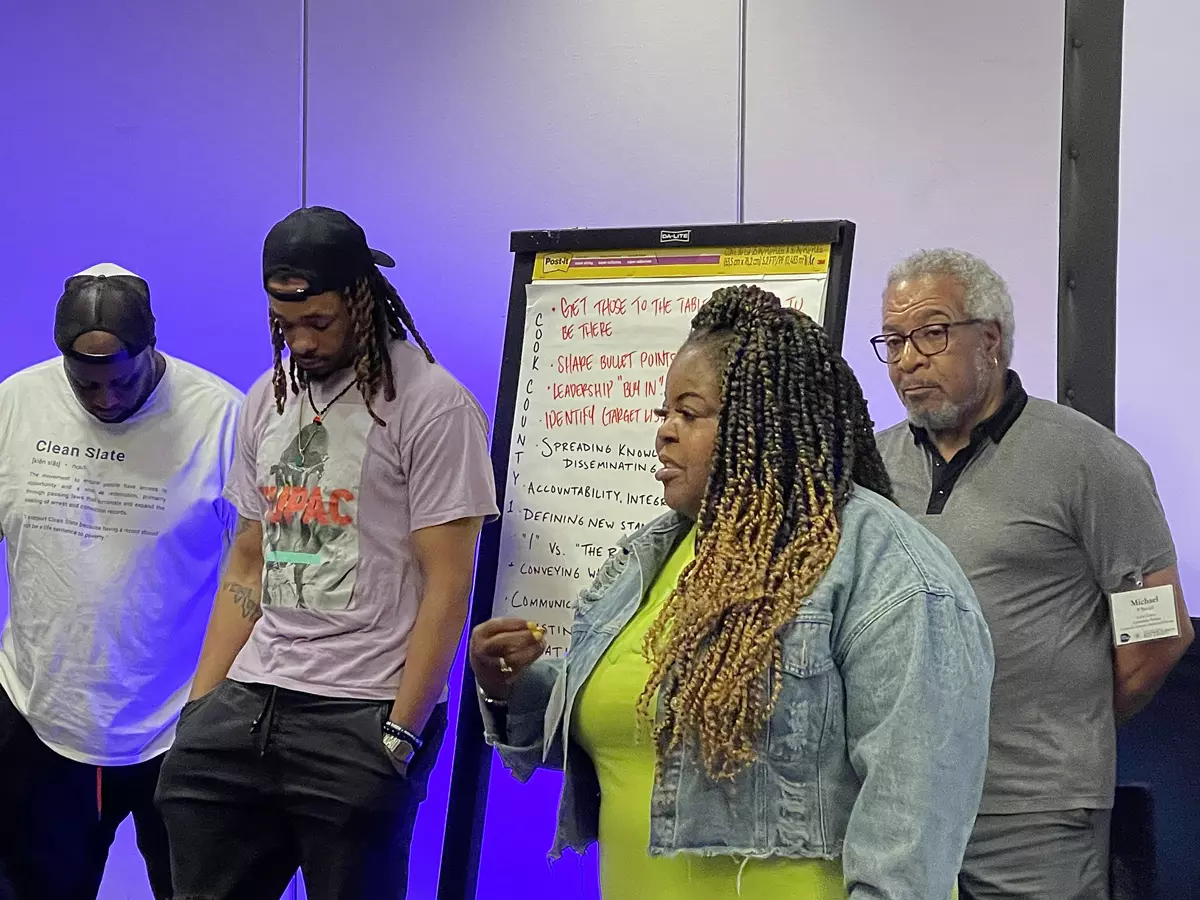 A person speaking with a large drawing pad and three people behind them.